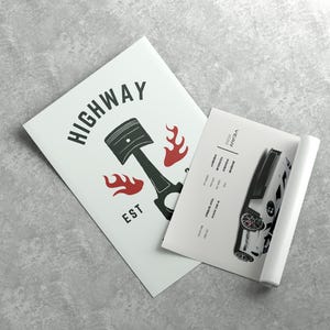May include: A white poster with black text that reads "HIGHWAY EST" and a black and white illustration of a piston with red flames. A second white poster with black text and a black and white illustration of a car is partially visible.