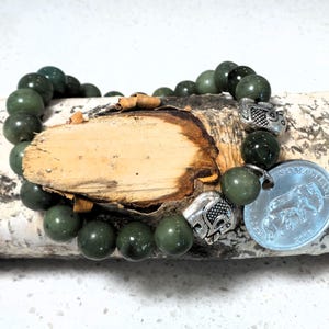 May include: A green jade beaded bracelet with silver elephant charms and a silver coin with the text "SOMALIA" and an elephant design.