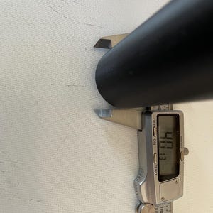 May include: A silver digital caliper measuring a black cylindrical object. The caliper reads 40.8 mm.