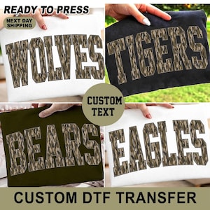 May include: A collection of four fabric transfers featuring the words WOLVES, TIGERS, BEARS, and EAGLES in a block varsity font. Each letter has a brown and green camouflage pattern with a dark outline, designed for heat application to apparel.
