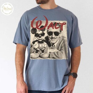May include: A blue short-sleeved t-shirt with a vintage graphic. The graphic shows Mickey Mouse in sunglasses and Walt Disney, with the name "Walt" in red script. The image is a distressed, sepia-toned design.