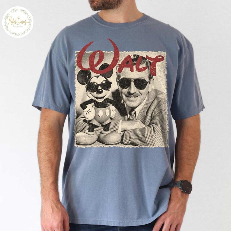 May include: A blue short-sleeved t-shirt with a vintage graphic. The graphic shows Mickey Mouse in sunglasses and Walt Disney, with the name "Walt" in red script. The image is a distressed, sepia-toned design.