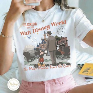 Puede incluir: Camiseta blanca con un gr&aacute;fico retro de Walt Disney World. El dise&ntilde;o incluye a Mickey Mouse, un hombre con traje, el castillo de Cenicienta y el texto "Florida Walt Disney World The Most Magical Place On Earth."