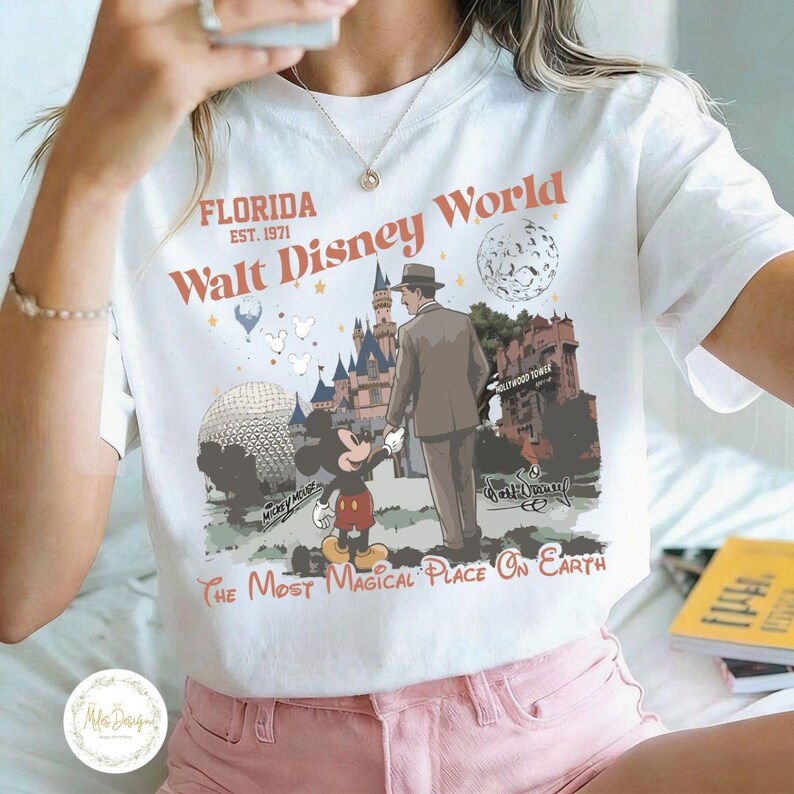 Puede incluir: Camiseta blanca con un gr&aacute;fico retro de Walt Disney World. El dise&ntilde;o incluye a Mickey Mouse, un hombre con traje, el castillo de Cenicienta y el texto "Florida Walt Disney World The Most Magical Place On Earth."