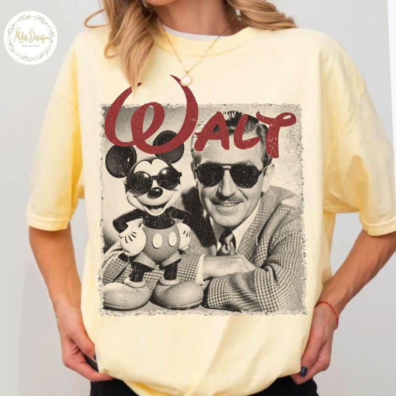 May include: A pale yellow t-shirt with a retro graphic of Mickey Mouse and Walt Disney wearing sunglasses. The word "WALT" is printed in red above the image. The shirt has short sleeves and a crew neck.
