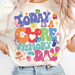 May include: A white t-shirt with a colourful graphic design featuring the characters from the movie Inside Out. The graphic says "Today is a Core Memory Day" with a Mickey Mouse head and a Disney castle.
