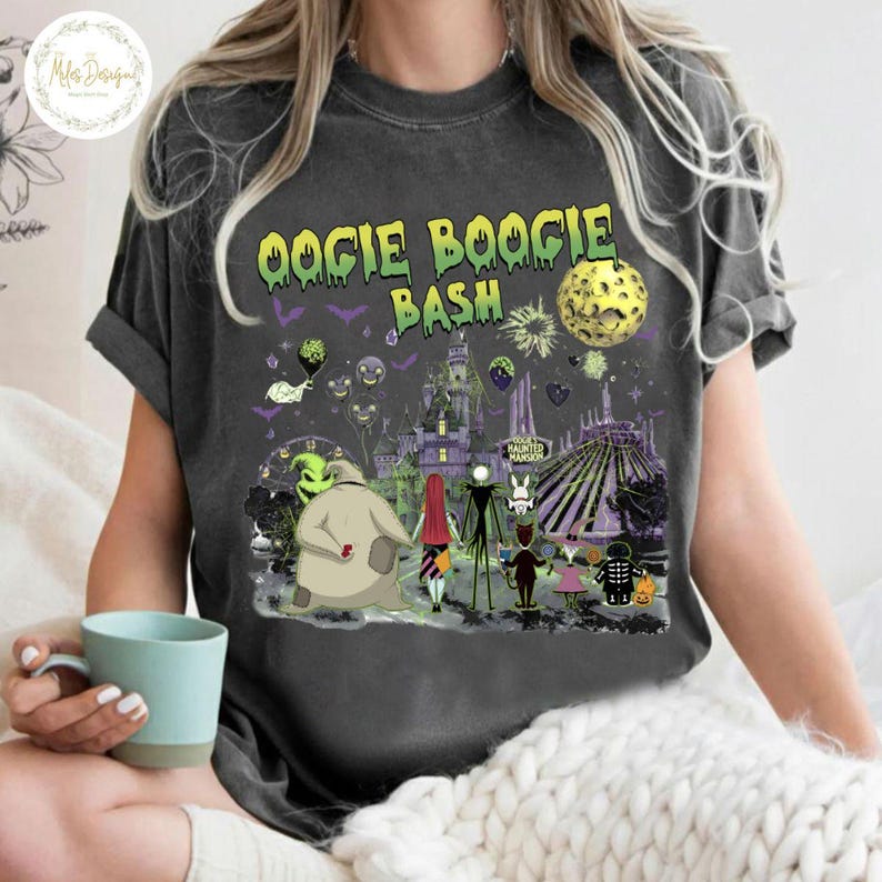 May include: Dark gray t-shirt with the text "Oogie Boogie Bash" in yellow and green. The shirt features a colorful graphic of characters and scenes from a Halloween-themed movie, including a full moon and a haunted house.