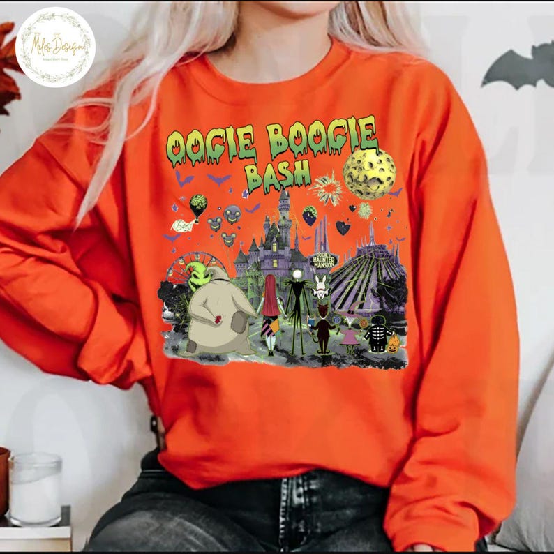 May include: Orange long-sleeve sweatshirt with a graphic featuring characters and scenes from "The Nightmare Before Christmas" and the text "Oogie Boogie Bash". The design includes a haunted house, a roller coaster, and a full moon.
