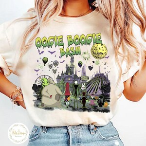 May include: Cream-colored t-shirt featuring a colorful graphic of characters and scenes from "The Nightmare Before Christmas" movie. The text "Oogie Boogie Bash" is in green above the image. The design includes a castle, a Ferris wheel, and a full moon.