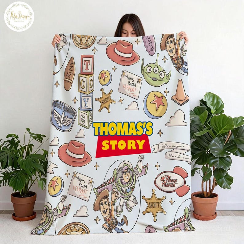 May include: A light blue blanket featuring cartoon characters and elements from the movie Toy Story. The blanket includes the text "THOMAS'S STORY" in a red and yellow design, along with images of Woody, Buzz Lightyear, and other characters.