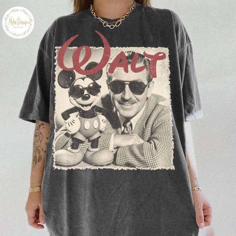 May include: Charcoal grey t-shirt with a retro graphic of Mickey Mouse in sunglasses and Walt Disney, with the name "Walt" in red script. The design has a distressed, aged appearance, giving it a vintage feel.