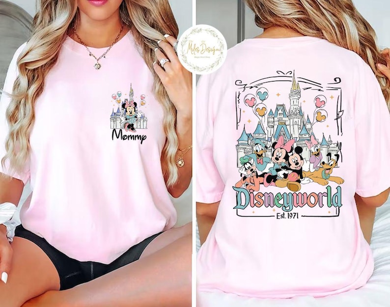 Pu&ograve; includere: Maglietta rosa con una grafica di Topolino e i suoi amici davanti al Castello di Cenerentola. Il testo "Disneyworld Est. 1971" &egrave; stampato sotto la grafica. La parte anteriore della maglietta ha una grafica pi&ugrave; piccola di Minnie Mouse davanti al Castello di Cenerentola con il testo "Mommy".
