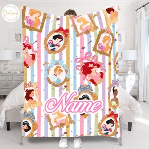 May include: A personalized blanket featuring portraits of Disney princesses in ornate frames against a striped background of pastel colors. The word "Name" is written in a cursive font. The blanket is held up by a person.