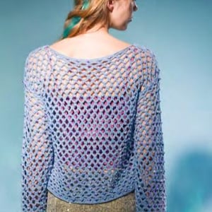 Könnte beinhalten: Ein hellblauer Häkelpullover mit lockerer Passform und langen Ärmeln. Der Pullover hat ein großes, offenes Strickmuster.