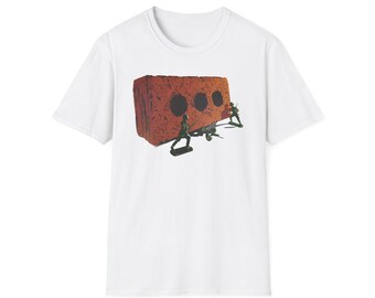 Könnte beinhalten: Weißes T-Shirt mit einer Grafik einer Backsteinmauer mit drei Löchern und Spielzeugsoldaten. Der Backstein ist rotbraun und die Spielzeugsoldaten sind grün. Das Design ist mittig auf der Vorderseite des T-Shirts.