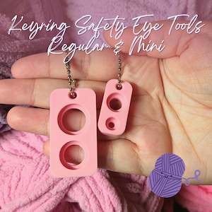 May include: Two pink keyring safety eye tools, regular and mini sizes, with silver chain attachments. The larger tool has two circular openings, while the smaller one has two smaller openings. Text on the image reads "Keyring Safety Eye Tools Regular & Mini."