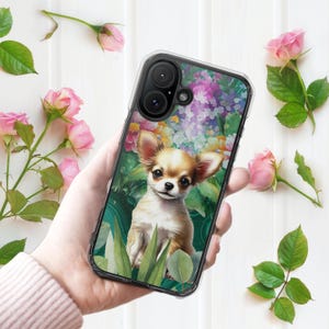 Peut inclure: Une coque de smartphone transparente ornée d'un motif imprimé représentant un chiot chihuahua beige et blanc assis parmi des feuilles vertes et des fleurs colorées. La coque présente des découpes précises pour les deux objectifs et le flash.