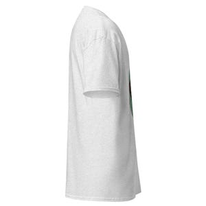 May include: A light gray t-shirt with a short sleeve design. The shirt has a crew neck and a side view. The fabric appears to be a soft, heathered material.