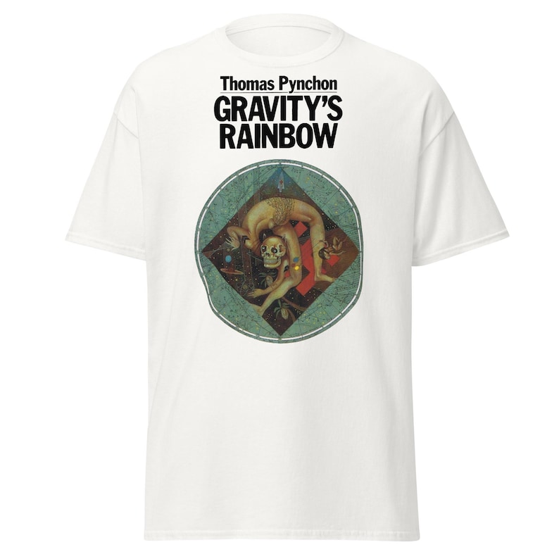 May include: White t-shirt featuring the text "Thomas Pynchon GRAVITY'S RAINBOW" in black. The shirt has a circular graphic with a figure in a contorted pose, with a skull and other figures.