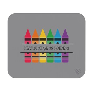 May include: A gray mousepad with a rainbow of crayons and the text "KNOWLEDGE IS POWER!" in black.