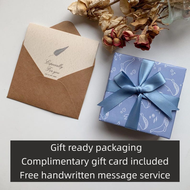 May include: A gift set with a light blue box wrapped with a blue satin ribbon and a brown envelope with a card that reads "Especially For You". The gift box is wrapped in paper with a whale pattern.