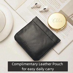 May include: A black leather pouch with the word "Galbacia" embossed on the front. A gold compact mirror with the name "Chloe" engraved on it and a pair of white wireless earbuds are also visible. The text "COMPLIMENTARY LEATHER POUCH for easy daily carry" is at the bottom.