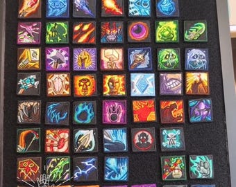 May include: A collection of square embroidered patches arranged in a grid on a black display board. Each patch features a unique, colorful graphic design, including various fantasy-themed icons, symbols, weapons, and character portraits.