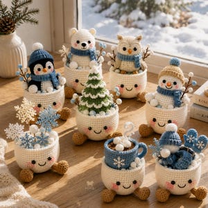 Puede incluir: Una colección de ocho figuras de ganchillo en tazas de color crema con caras sonrientes y mejillas rosadas. Las figuras incluyen un pingüino, un oso polar, un búho, un muñeco de nieve, un árbol de Navidad, copos de nieve, una taza azul y manoplas.