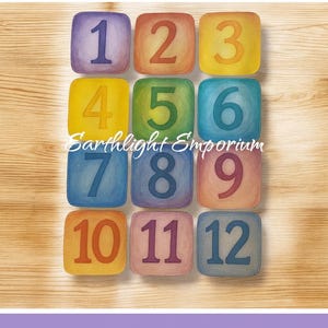 May include: Watercolor Waldorf-inspired number cards, featuring numbers 1-12 in a colorful, watercolor style. Each number is displayed on a square with a unique color. The text "Earthlight Emporium" is also visible. The words "Digital Download" are at the bottom.