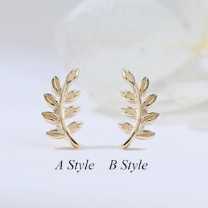 May include: Two gold-toned metal stud earrings shaped like small leafy branches. The left earring is labeled A Style and the right earring is labeled B Style. Each earring features a central stem with multiple small, oval-shaped leaves extending outward.