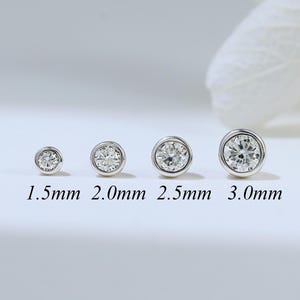 Op de afbeelding: Vier zilverkleurige oorknopjes met heldere ronde stenen in een gladde zetting, gerangschikt in een rij van klein naar groot. De maten staan onder elk oorknopje vermeld als 1,5 mm, 2,0 mm, 2,5 mm en 3,0 mm voor de diameter van elk sieraad.