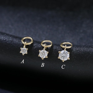 May include: Three gold-coloured, star-shaped charms with clear gemstones are displayed on a dark surface. Each charm is labelled with a letter: A, B, and C. The charms are designed for jewellery making.