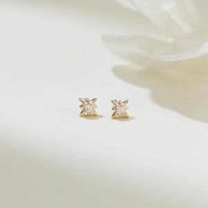 May include: A pair of gold star-shaped earrings with a small clear stone in the center of each star.