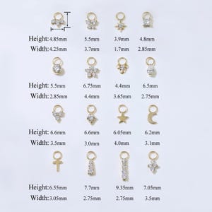 Puede incluir: Una colecci&oacute;n de colgantes de joyer&iacute;a dorados en varias formas, incluyendo estrellas, flores y dise&ntilde;os geom&eacute;tricos. Las medidas est&aacute;n en mil&iacute;metros, con alturas que van desde 4,85 mm hasta 6,6 mm y anchos de 1,7 mm a 4,25 mm. Cada colgante tiene un peque&ntilde;o lazo.