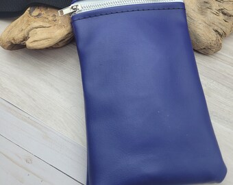 Puede incluir: Una pequeña bolsa azul con cremallera y una correa negra. La bolsa está hecha de un material similar al cuero.
