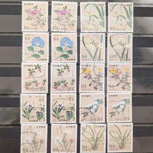 以下が含まれることがあります： 様々な色の花のイラストが描かれた16枚の日本の切手のコレクション。切手には「84 NIPPON」の文字と日本語の文字が表示されています。切手は4列4行に配置されています。