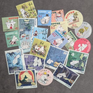 以下が含まれることがあります： 漫画のキャラクターと日本語のテキストが特徴の、カラフルなヴィンテージ切手のコレクション。切手は様々な形とサイズで、82、84、110、62などの価値があります。切手は暗い表面に配置されています。