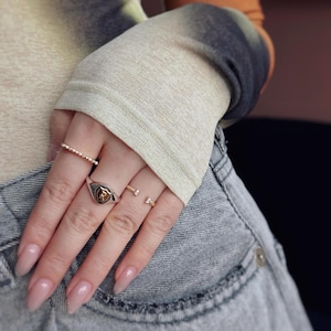 La herencia de un antiguo sello de cera se fusiona con el místico oro de dos tonos de 9 quilates: un anillo con letras personalizadas que representa amor y poder atemporales.