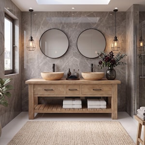 May include: A wooden double vanity featuring two light-colored stone vessel sinks, black faucets, and three drawers with black hardware. Below, a slatted shelf holds folded white towels. Two round mirrors hang above, flanked by hanging cage lights.