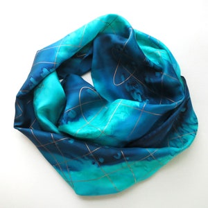 Silk scarf in light and dark blues, wrapped in a circle on a flat white surface to show the overall color pattern.