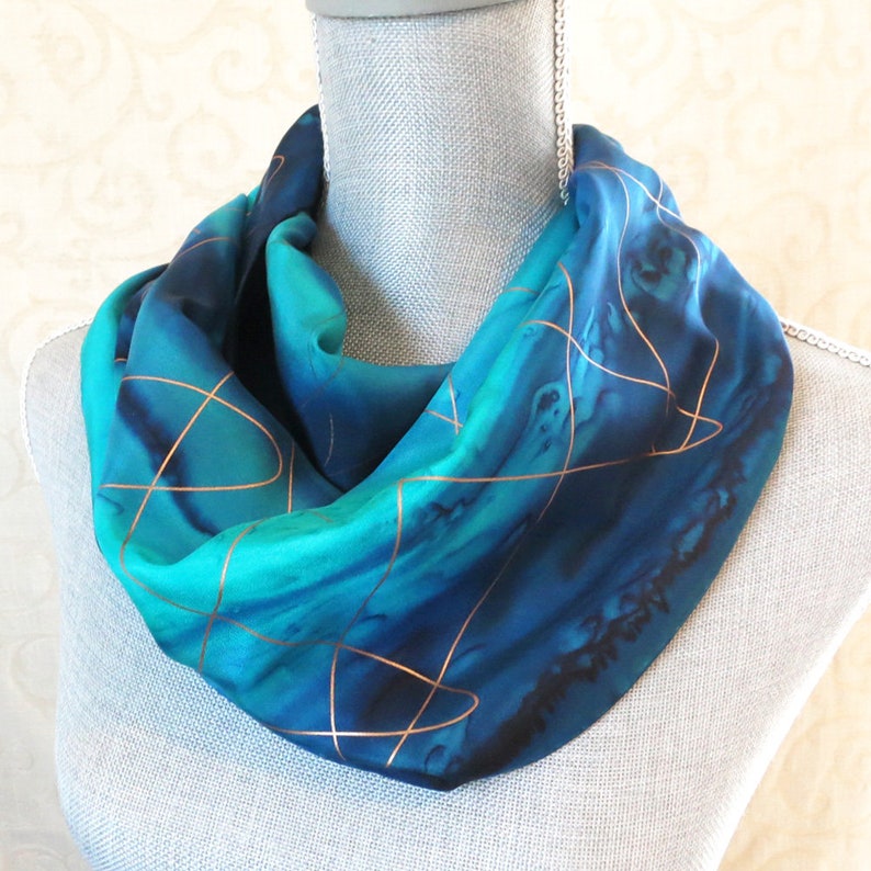 Silk scarf dyed in shades of blue gathered around neck of mannequin highlighting the width of the scarf of approximately 11".