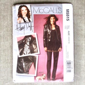 May include: A McCall's sewing pattern, M5515, featuring a woman in a black leather jacket and pants. The pattern includes images of the jacket and a small dog. The pattern also includes the signature of Hilary Duff.