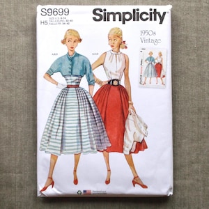 May include: A vintage Simplicity sewing pattern, S9699, featuring illustrations of 1950s dresses. The pattern includes sizes 6-14. The cover displays two women in dresses, one in a blue top and striped skirt, the other in a white top and red skirt.