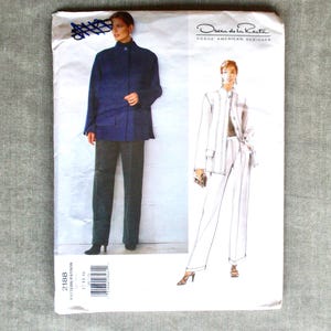 May include: A vintage sewing pattern featuring an illustration of a woman in a navy blue jacket and gray pants. The pattern is labeled "Oscar de la Renta, Vogue American Designer". The pattern number is 2188.