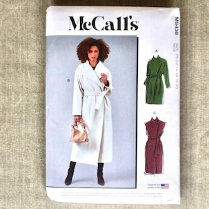 May include: A McCall's sewing pattern envelope featuring a woman in a white coat with a belt. The envelope also shows illustrations of a green coat and a burgundy dress. The text on the envelope includes "McCall's" and "M8438".
