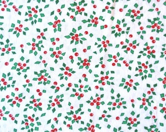 May include: A white fabric featuring a repeating pattern of small red berries and green diamond-shaped leaves. The design is evenly distributed across the surface, showcasing clusters of three red dots surrounded by several small green geometric shapes.
