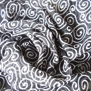 May include: Black and white fabric with a swirling pattern. The fabric is sheer and has a delicate texture.