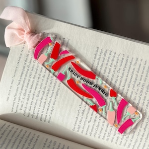 Könnte beinhalten: Ein transparentes Acryl-Lesezeichen mit einem Design aus roten, rosa und grünen Chilischoten. Das Lesezeichen trägt den Text "Spicy Book Junkie".