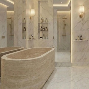 Puede incluir: Un lujoso ba&ntilde;o con una gran ba&ntilde;era de piedra beige como punto focal. Las paredes y el suelo est&aacute;n cubiertos de m&aacute;rmol blanco, y hay estantes empotrados con art&iacute;culos de tocador. El espacio est&aacute; iluminado por una iluminaci&oacute;n suave y apliques.