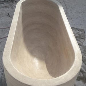 Puede incluir: Una ba&ntilde;era ovalada beige de piedra. La ba&ntilde;era tiene un interior liso y un exterior redondeado. El accesorio de ba&ntilde;o est&aacute; dise&ntilde;ado para remojarse y relajarse. La ba&ntilde;era es de color neutro, adecuada para varios estilos de ba&ntilde;o.